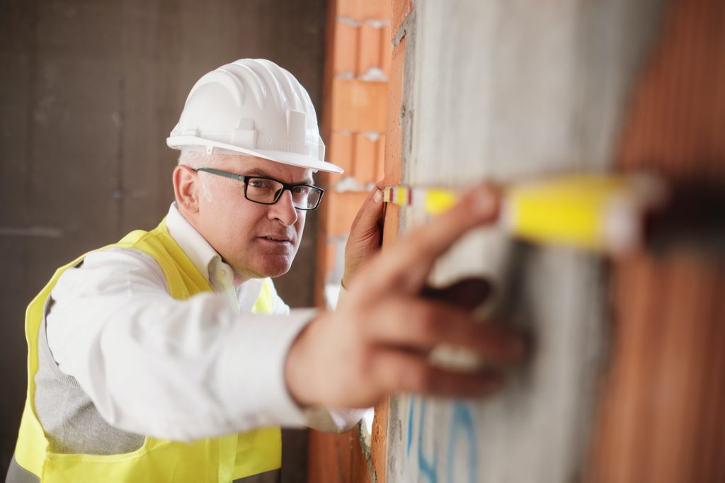Man Working As Architect Measuring Wall In Construction Site
